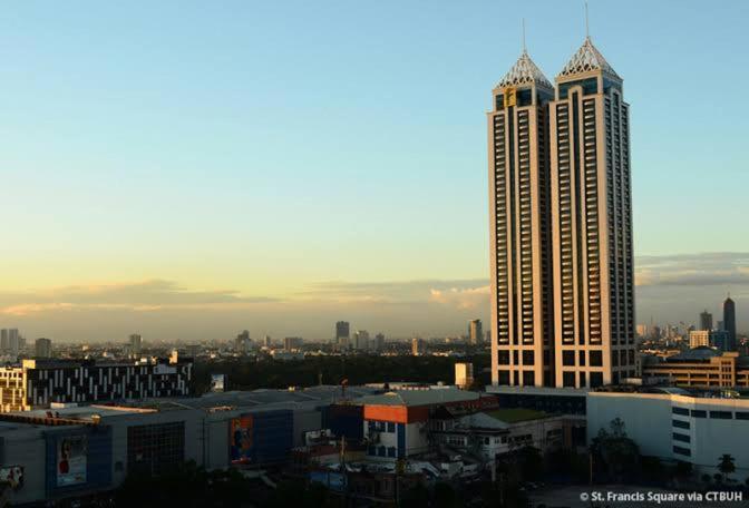 a view of a city with a tall building at Posh Beds with City View and Pools in Manila