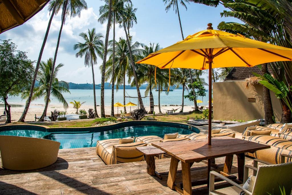 庫德島的住宿－Tolani Resort Koh Kood，游泳池旁带遮阳伞的桌子