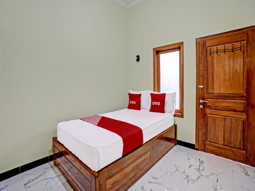 a bedroom with a bed with red pillows and a door at OYO Life 92043 Kost Barokah Syariah Madiun in Madiun
