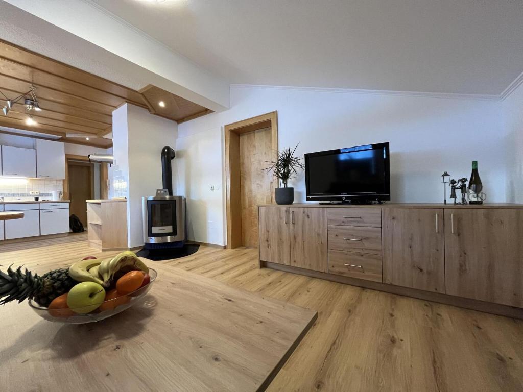 - un salon avec une télévision et une corbeille de fruits dans l'établissement Cozy apartment in Wald im Pinzgau with balcony and barbecue area, à Wald im Pinzgau