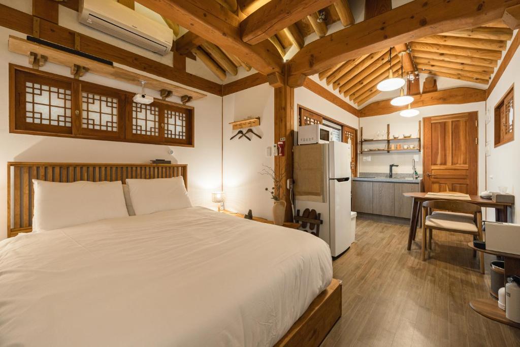 a bedroom with a white bed and a kitchen at Luxury hanok with private bathtub - SN11 in Seoul