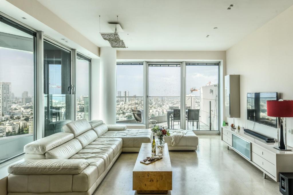 ein Wohnzimmer mit einem Sofa und großen Fenstern in der Unterkunft Luxury 2 BR Apt w Pool & Panoramic View by Sea N' Rent in Tel Aviv