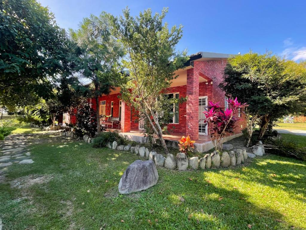 a red brick house with a rock in the yard at Happiness AIR B&B in Guanshan