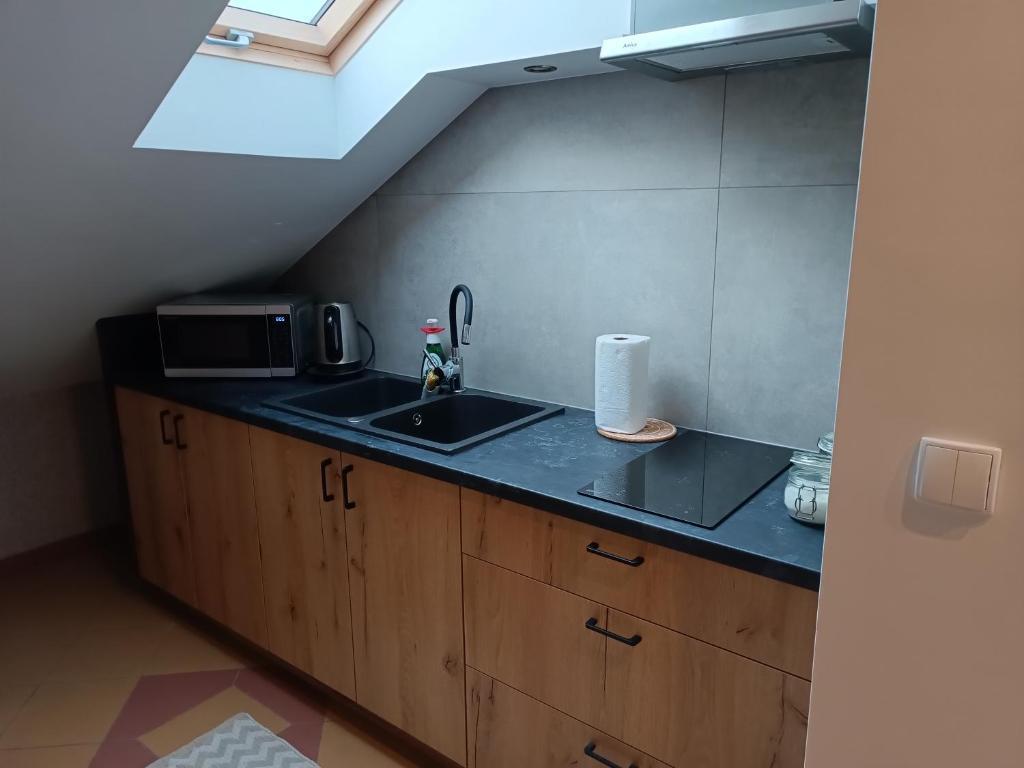 eine Küche mit einer Spüle und einer Mikrowelle in der Unterkunft Restauracja Rozmarzyn in Schildberg