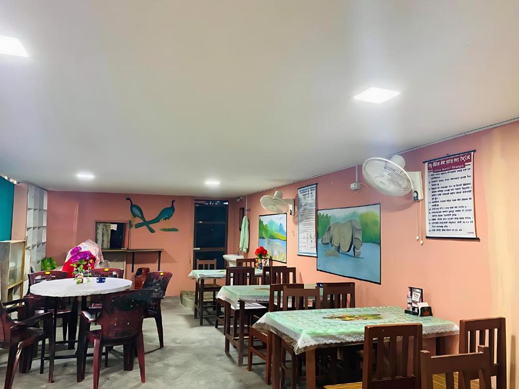 comedor con mesas, sillas y paredes rosas en Hotel BhupuSainik Sauraha, en Sauraha