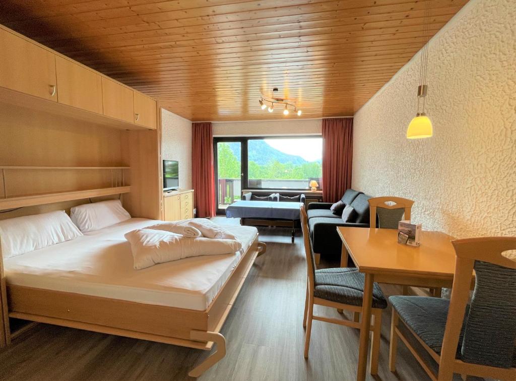 a hotel room with a bed and a dining room at Allgäu Appartementhaus Appartement ALLGÄU 14 in Pfronten