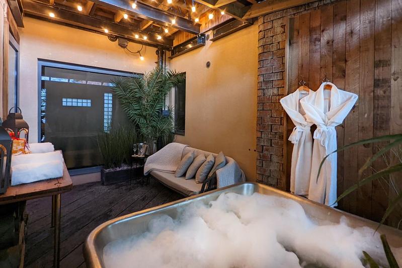 a bath tub in a room with a couch and a robe at The Bells - Luxury Serviced Apartments in Leeds