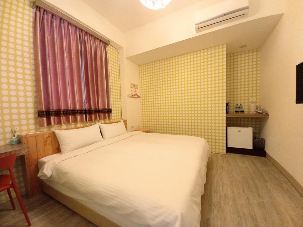 a bedroom with a white bed and a window at Mixa Hostel in Hualien City