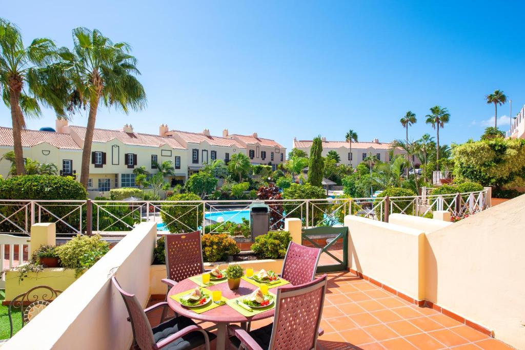 balcón con mesa, sillas y palmeras en Lovely Holiday in Golf del Sur en San Miguel de Abona