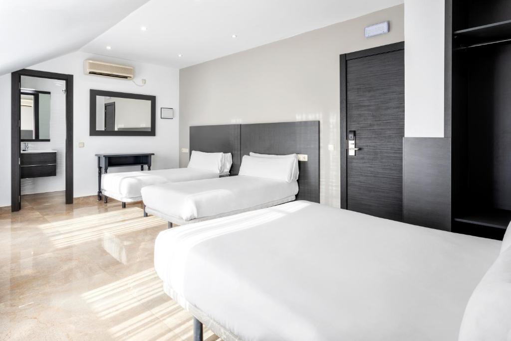 バルデモロにあるHotel Victoria Valdemoroのベッド2台とバスルームが備わるホテルルームです。