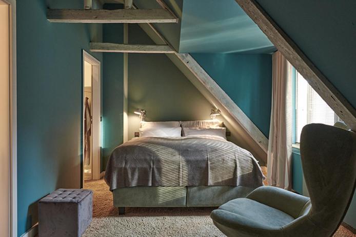 a bedroom with blue walls and a bed and a chair at Landhaus Jenischpark in Hamburg
