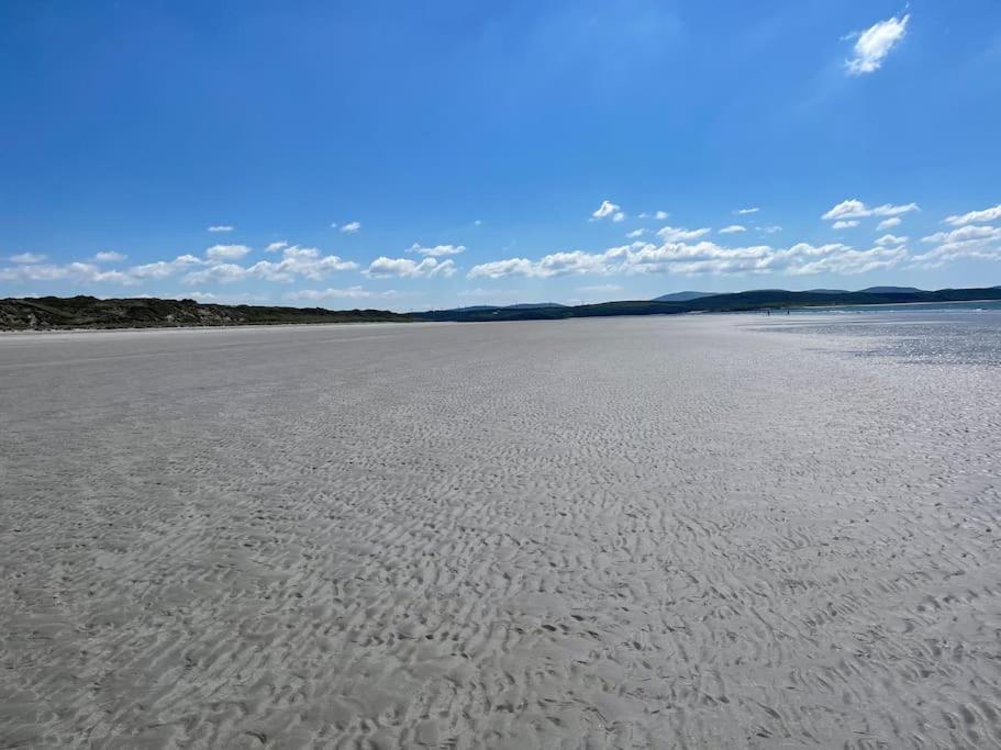 an empty beach with footprints in the sand at Donegal Beach Cottage with Sea Views, sleeps six in Lettermacaward