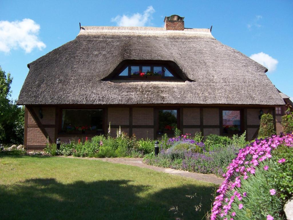 a house with a thatched roof with flowers at Boddenzauber in Fuhlendorf