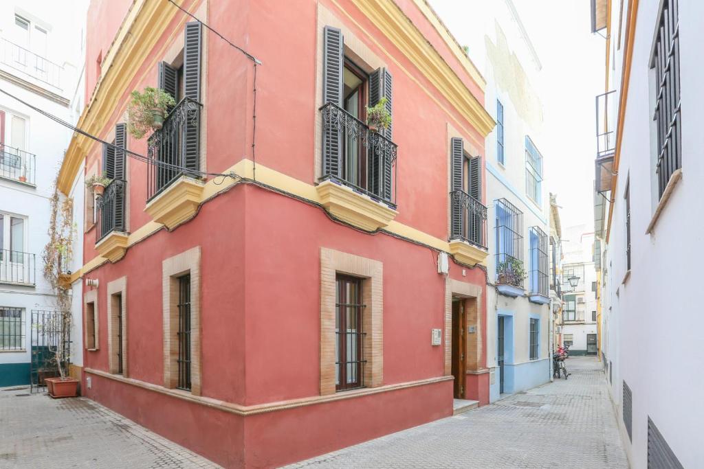 um edifício vermelho com janelas e varandas numa rua em Casa Sevillana em Sevilha