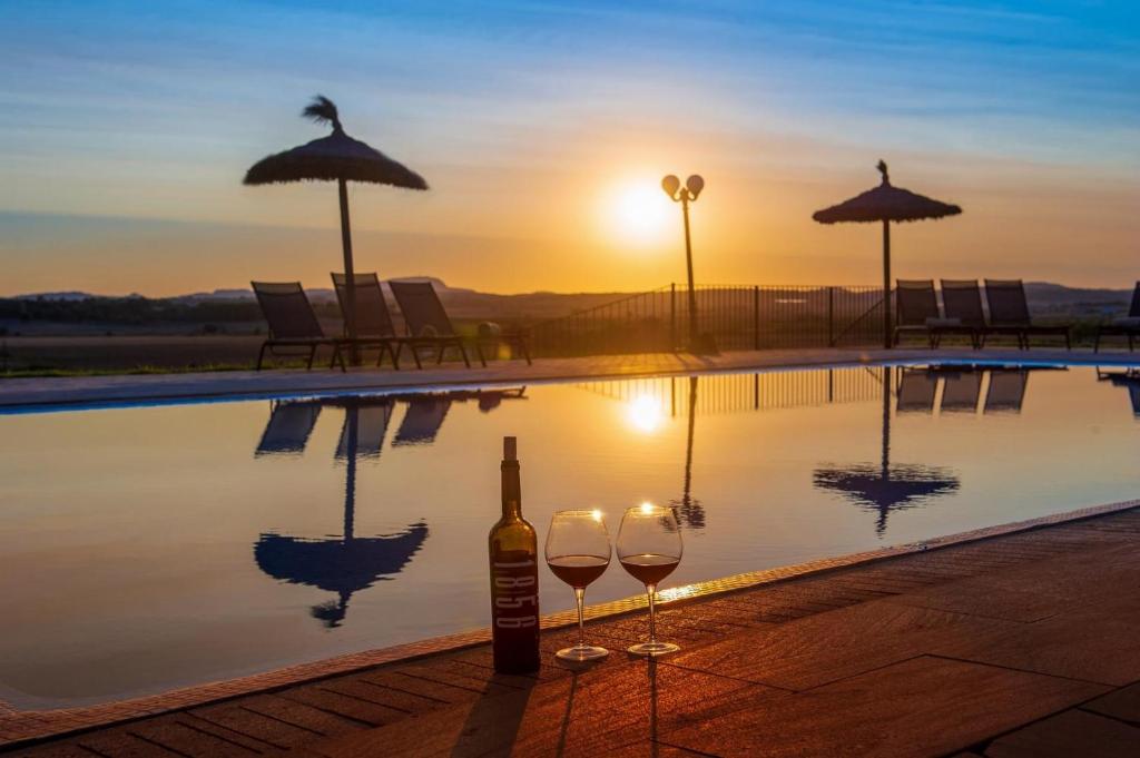 a bottle of wine and two glasses next to a swimming pool at Sa Franquesa Vella in Manacor
