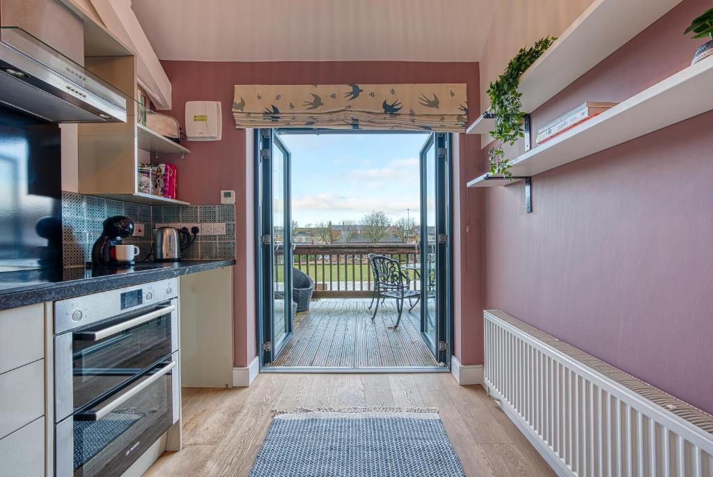 een keuken met een deur naar een balkon bij Ashcroft Loft by Apricity Property - Stunning 3 Bedroom, 2 bathrooms, Cosy Central Apartment with balcony in Cirencester