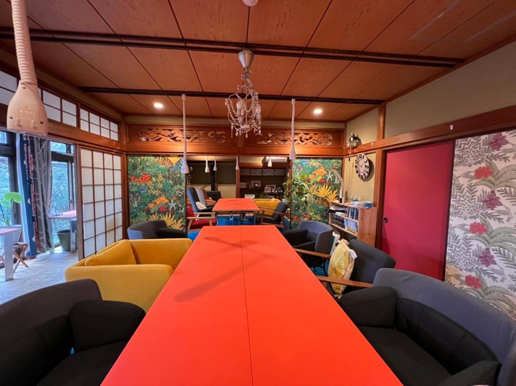 a long red table in a room with couches at Cozy and Cheap Kinosaki Hideya Non Japanese in Toyooka