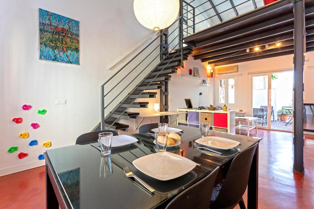 a dining room with a table with chairs and a staircase at Livemálaga Cervantes Attic & Terrace in Málaga