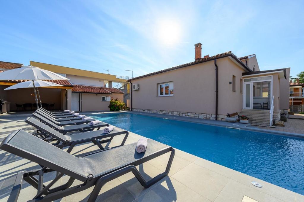 - une piscine avec 2 chaises longues et un parasol dans l'établissement Villa Jolanda, à Umag