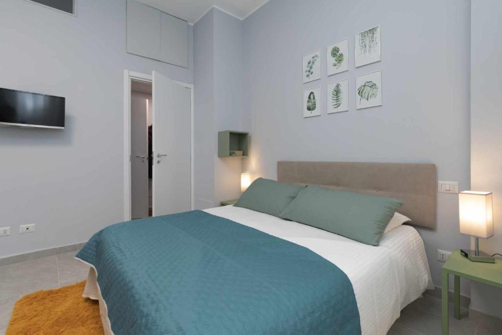 a white bedroom with a blue bed and a television at Montalbino place in Milan