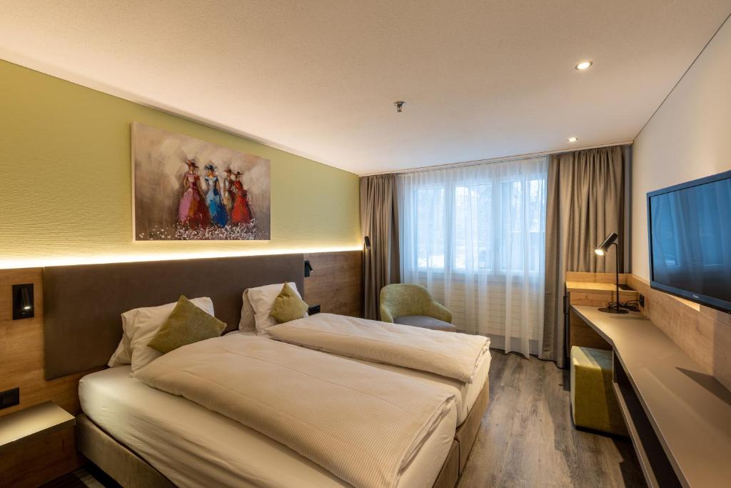 um quarto de hotel com duas camas e uma televisão de ecrã plano em Hotel Flamatt em Flamatt