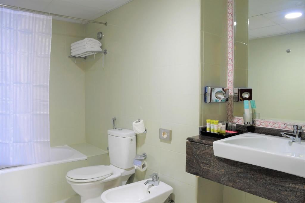 ein Badezimmer mit einem WC, einem Waschbecken und einer Badewanne in der Unterkunft Ramada by Wyndham Beach Hotel Ajman in Ajman 