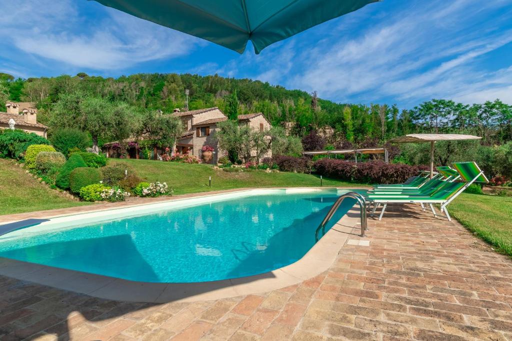 a swimming pool with two chairs and an umbrella at Italian Experience-Villa Emilianna in Rosciano