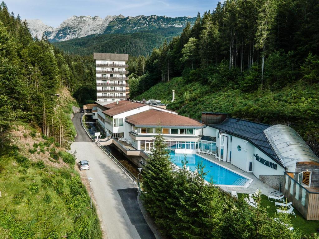 a house with a swimming pool next to a mountain at Gesundheit & Wellness Resort Bad Mitterndorf in Bad Mitterndorf