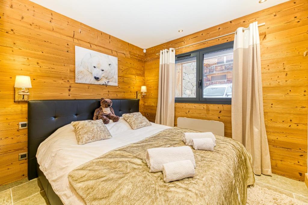 a bedroom with a large bed with a teddy bear on it at Alpes Sweet Home - Chalet La Biche in L&#39;Alpe-d&#39;Huez