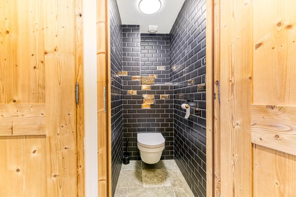 a bathroom with a toilet and a black brick wall at Alpes Sweet Home - Chalet La Biche in L&#39;Alpe-d&#39;Huez