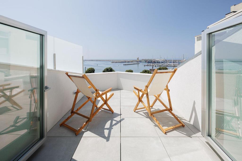 2 sillas en un balcón con vistas al océano en Lapa 84 - seafront house, en Póvoa de Varzim