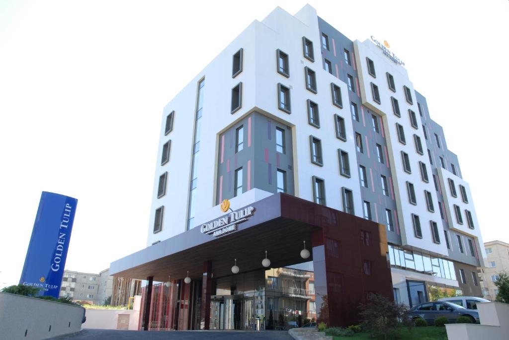 a white building with a sign on the side of it at Golden Tulip Ana Dome Hotel in Cluj-Napoca