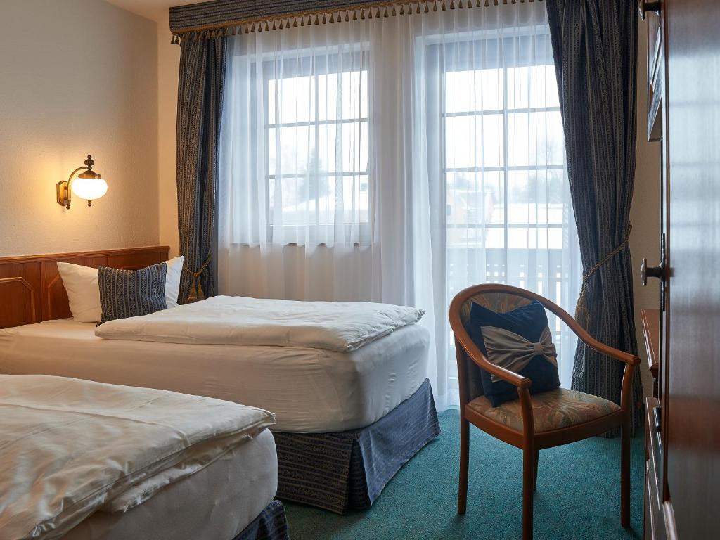 een hotelkamer met 2 bedden, een stoel en een raam bij Showhotel Seerose 