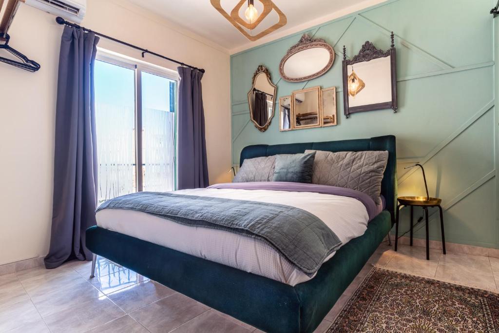 a bedroom with a bed with blue walls and a window at Arty Vintage Townhouse with Rooftop Shower & Sun Loungers in Olhão