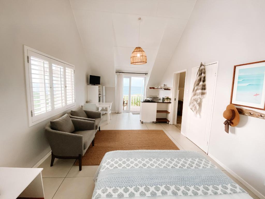 ein Schlafzimmer mit einem Bett, einem Sofa und einem Stuhl in der Unterkunft Pebbles Beach Cottage in Port Elizabeth