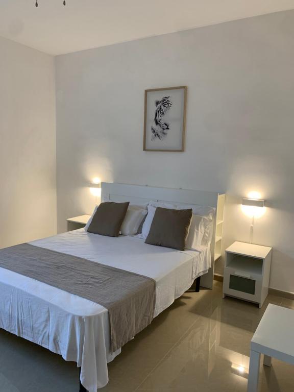 una camera da letto con un grande letto bianco e due tavoli di Il Canaletto Apartments a Porto Cesareo