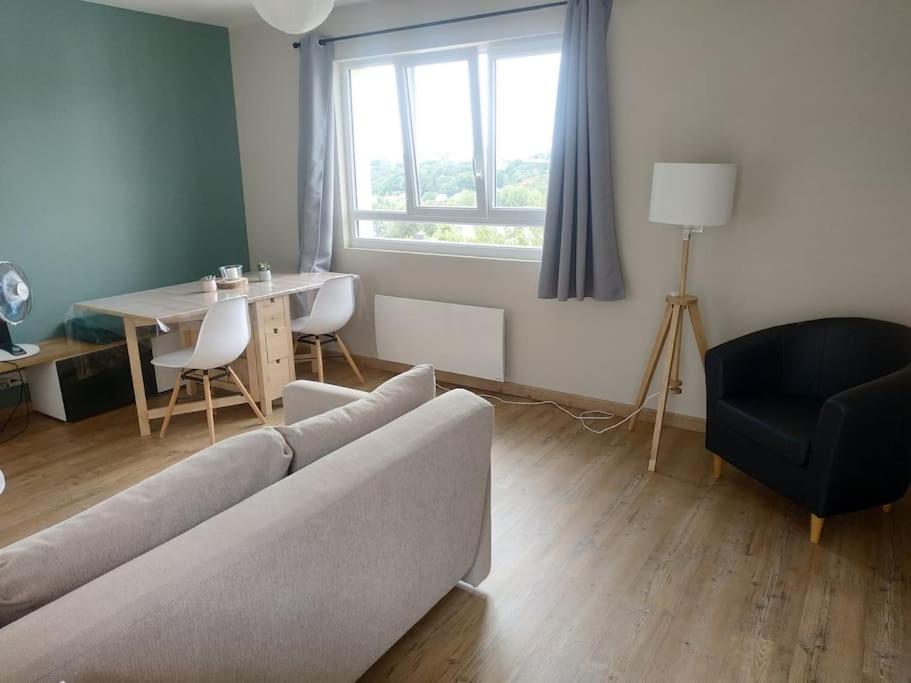 a living room with a couch and a table and a window at Jolie petite maison indépendante in Pont-de-Buis