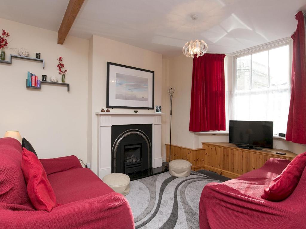 a living room with two red couches and a fireplace at Pass the Keys Comfortable Stone Built Cottage in Menai Bridge in Menai Bridge