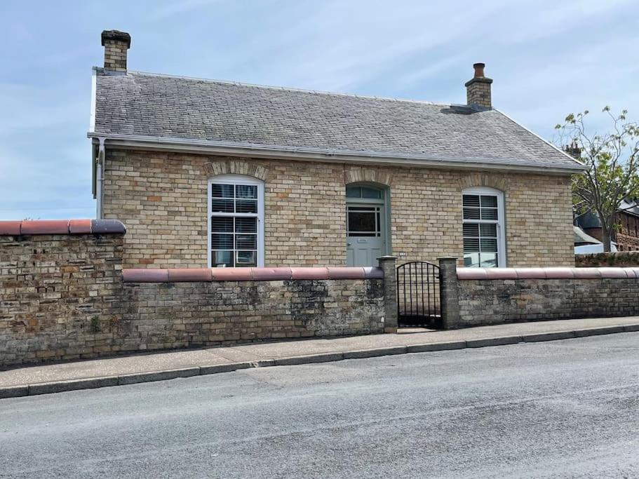 a brick house with a fence in front of a street at Traditional Cottage in West Kilbride Village in Seamill