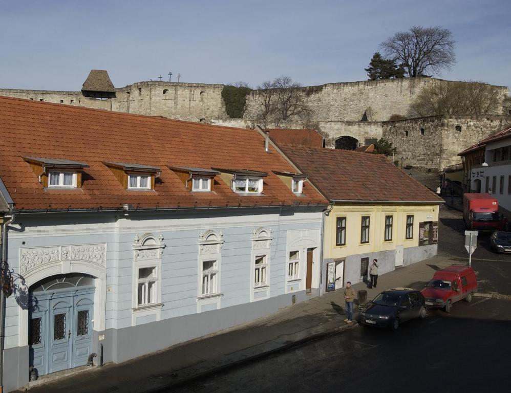 a white building with a red roof in front of a castle at Várkapu Panzió in Eger