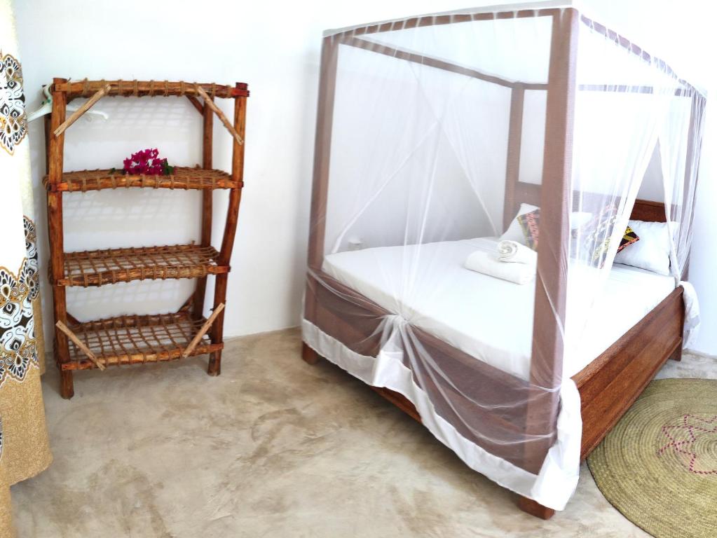 a bedroom with a canopy bed and a shelf at MaNa Nungwi in Nungwi