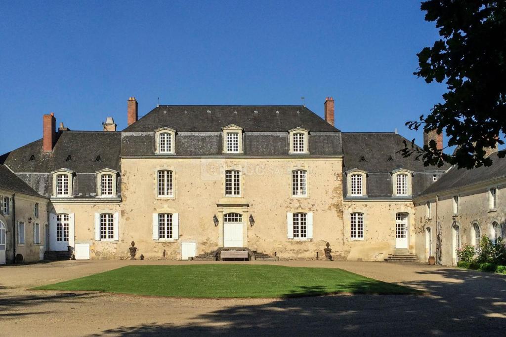 - un grand bâtiment en pierre avec une grande cour dans l'établissement Bel appartement à la Chetardière, à Sainte-Gemme-dʼAndigné