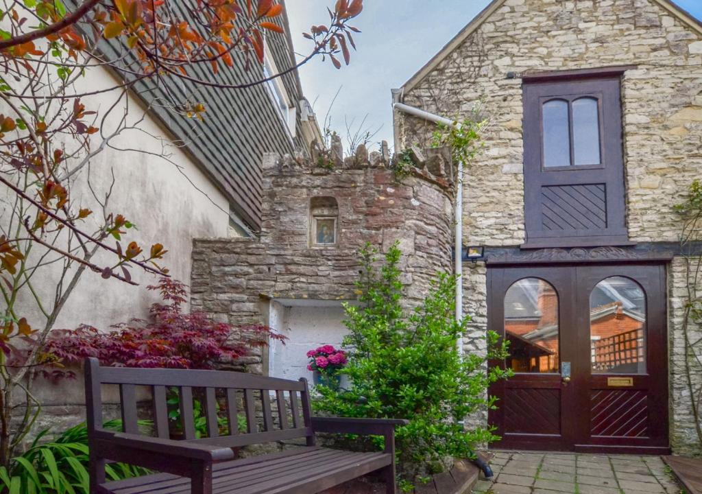 a wooden bench sitting in front of a stone house at The Smokery in Swanage