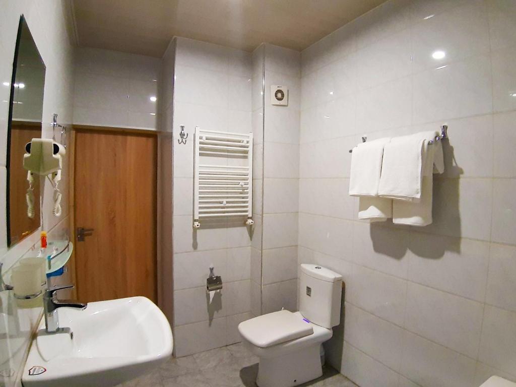 a bathroom with a white toilet and a sink at Al Arda HOTEL in Tashkent
