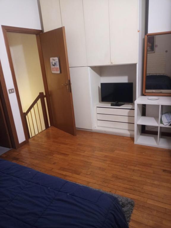 Habitación con cama, TV y suelo de madera. en Mazzini, en Forlì