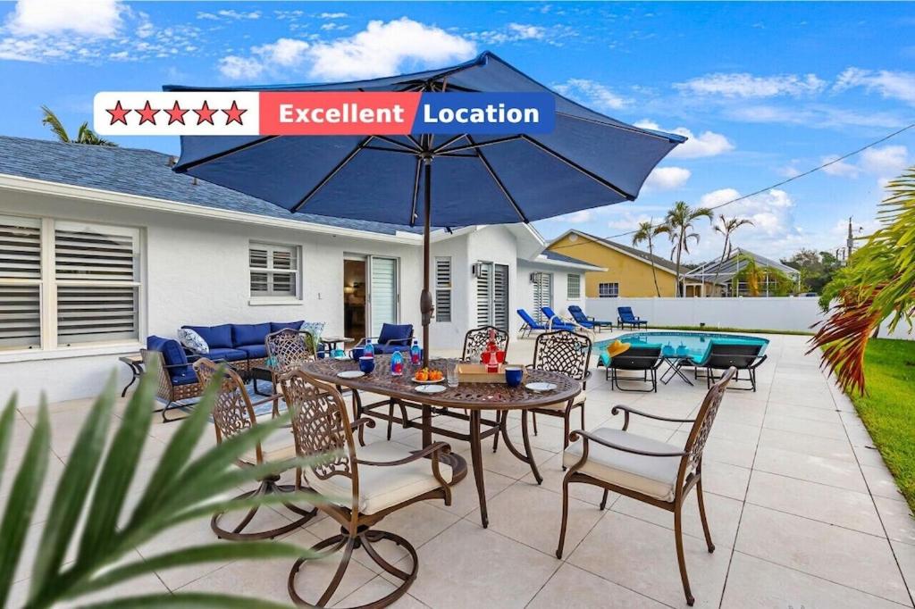 eine Terrasse mit einem Tisch, Stühlen und einem Sonnenschirm in der Unterkunft Private Pool｜Near Beach｜Fenced Yard｜Outdoor Living in Naples