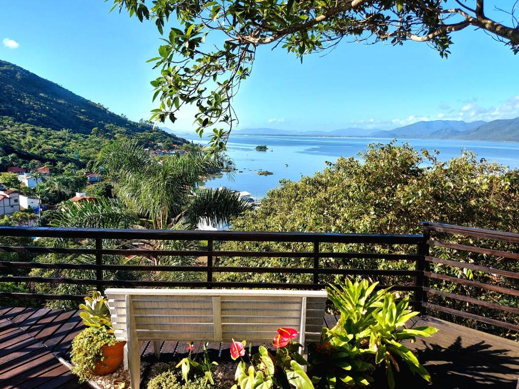 un banco sentado en un balcón con vistas al agua en Casa na montanha com vista para o mar, en Florianópolis