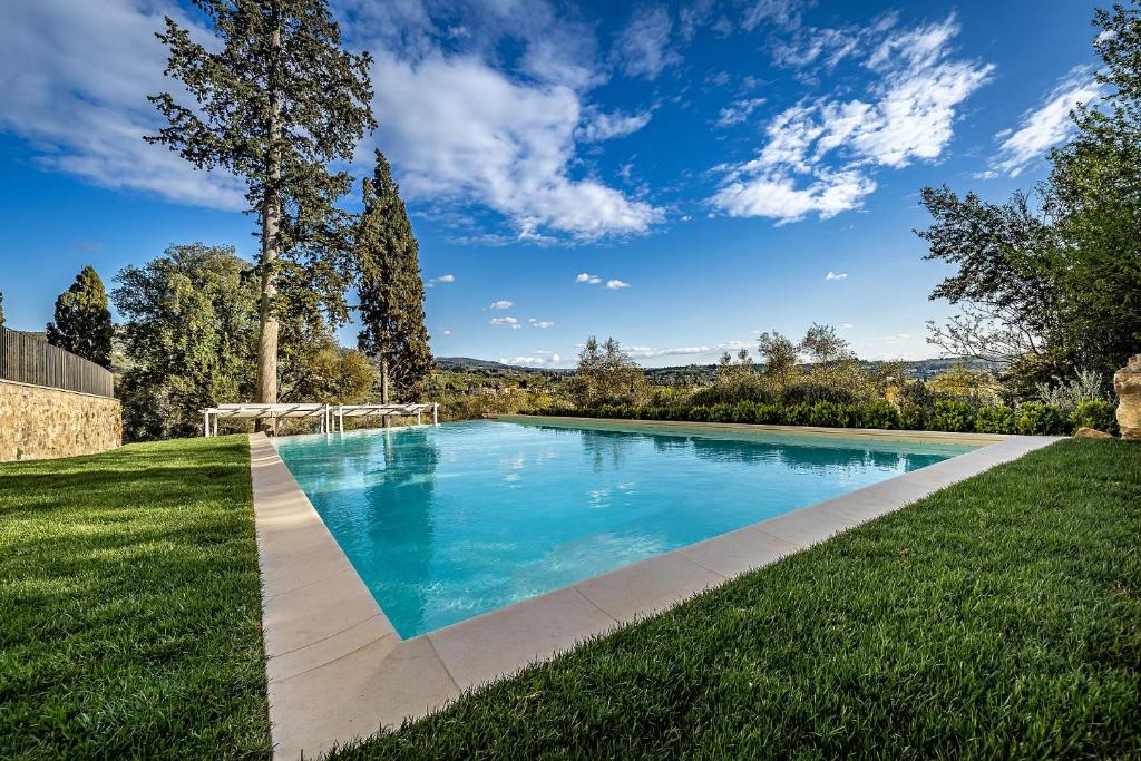 ein Pool in einem Garten mit grünem Gras in der Unterkunft Luxury Villa Tolomei Gucci near Florence in San Jacopo al Girone