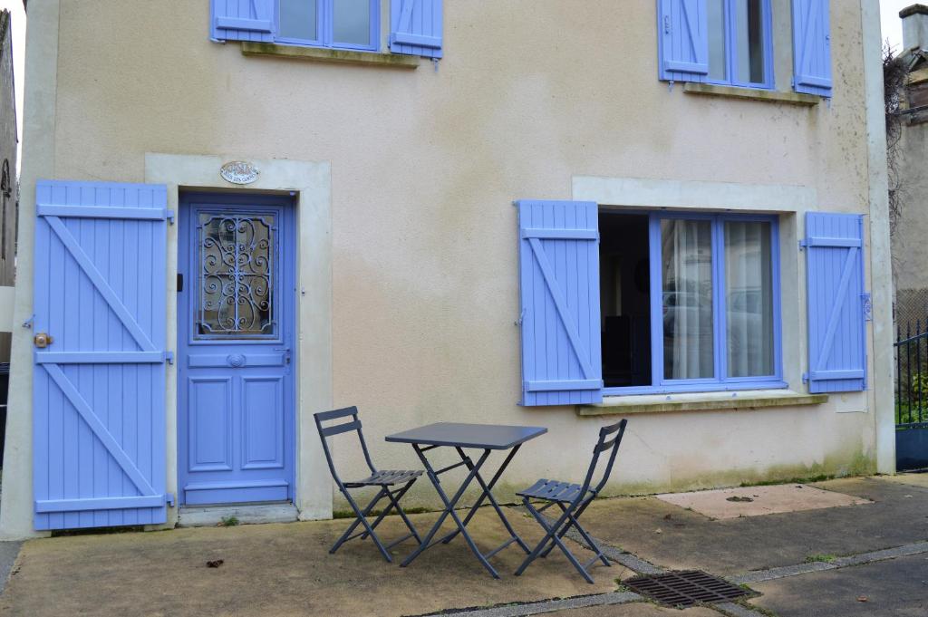 un tavolo e sedie di fronte a un edificio con porte blu di Les volets bleus - duplex proche plage et centre ad Arromanches-les-Bains