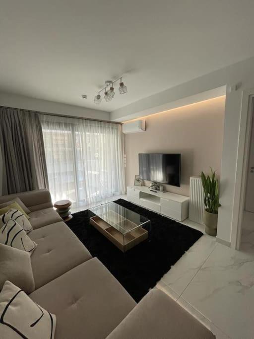 ein Wohnzimmer mit einem Sofa und einem TV in der Unterkunft Niarchos apartment III in Athen
